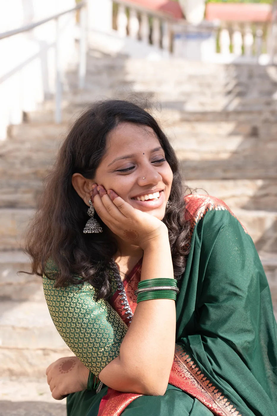 Woman in a green saree laughing in warm sunlight
