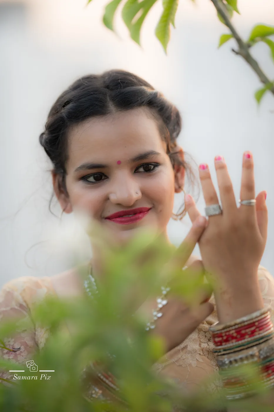 Young girl admiring her rings through green leaves